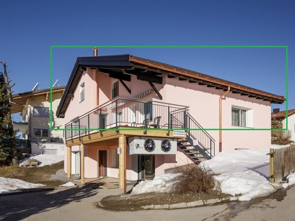 A two-story building with a balcony, a staircase, and a sign indicating a business.