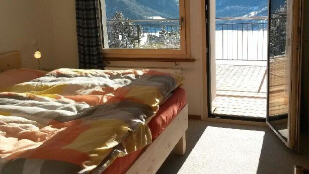 Una camera da letto con un letto, una finestra e vista sulle montagne e su un lago.