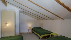 Una sistemazione modesta con una sola stanza, due letti, un comodino e una lampada fissata al muro.