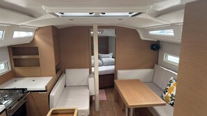 A compact RV interior with a kitchenette, a dining area, a seating space, and a sleeping area.