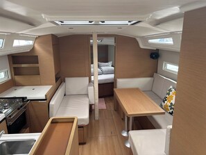 A compact RV interior with a kitchenette, a dining area, a seating space, and a sleeping area.