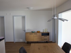 A dining area with a wooden table, chairs, a cabinet with decorative bowls, and a hanging light fixture. - Pardi 3 Simeon Appartement/Fewo 4.5 - Zimmerwohnung by Interhome (Lantsch)