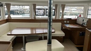 A boat interior with a dining area, a small kitchen, and a view of the marina. - Sun-Kissed Sailing Adventure in the Sporades Islands from Volos, Thessaly (Volos)