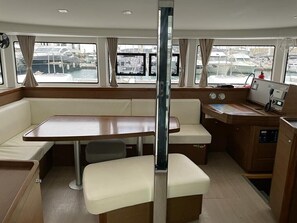 A boat interior with a dining area, a small kitchen, and a view of the marina. - Sun-Kissed Sailing Adventure in the Sporades Islands from Volos, Thessaly (Volos)
