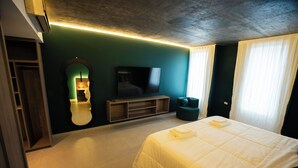 Ein Hotelzimmer mit Bett, Fernseher, Spiegel und einer Sitzecke.