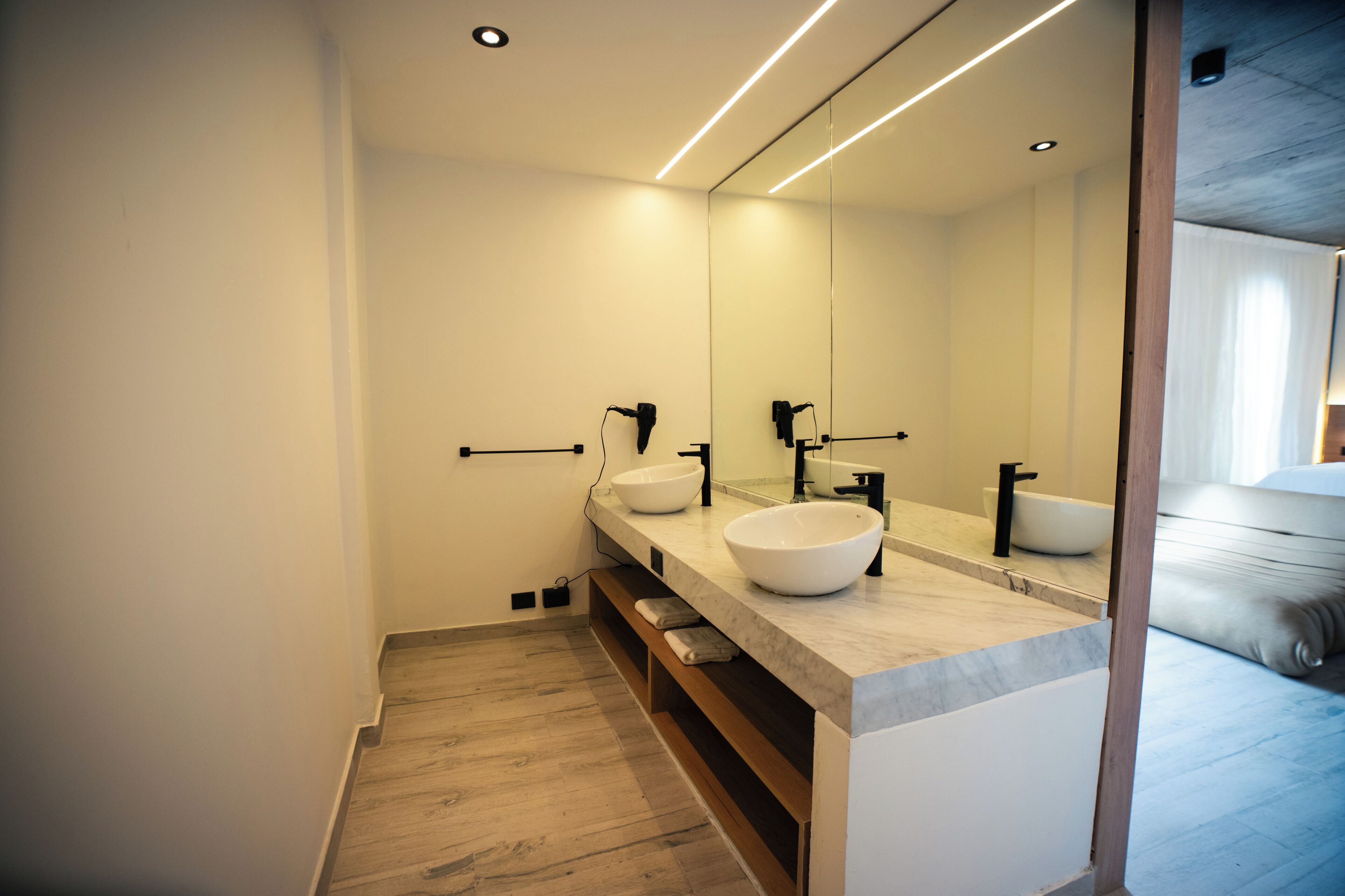 A modern bathroom with a large mirror, two sinks, and a wooden vanity.