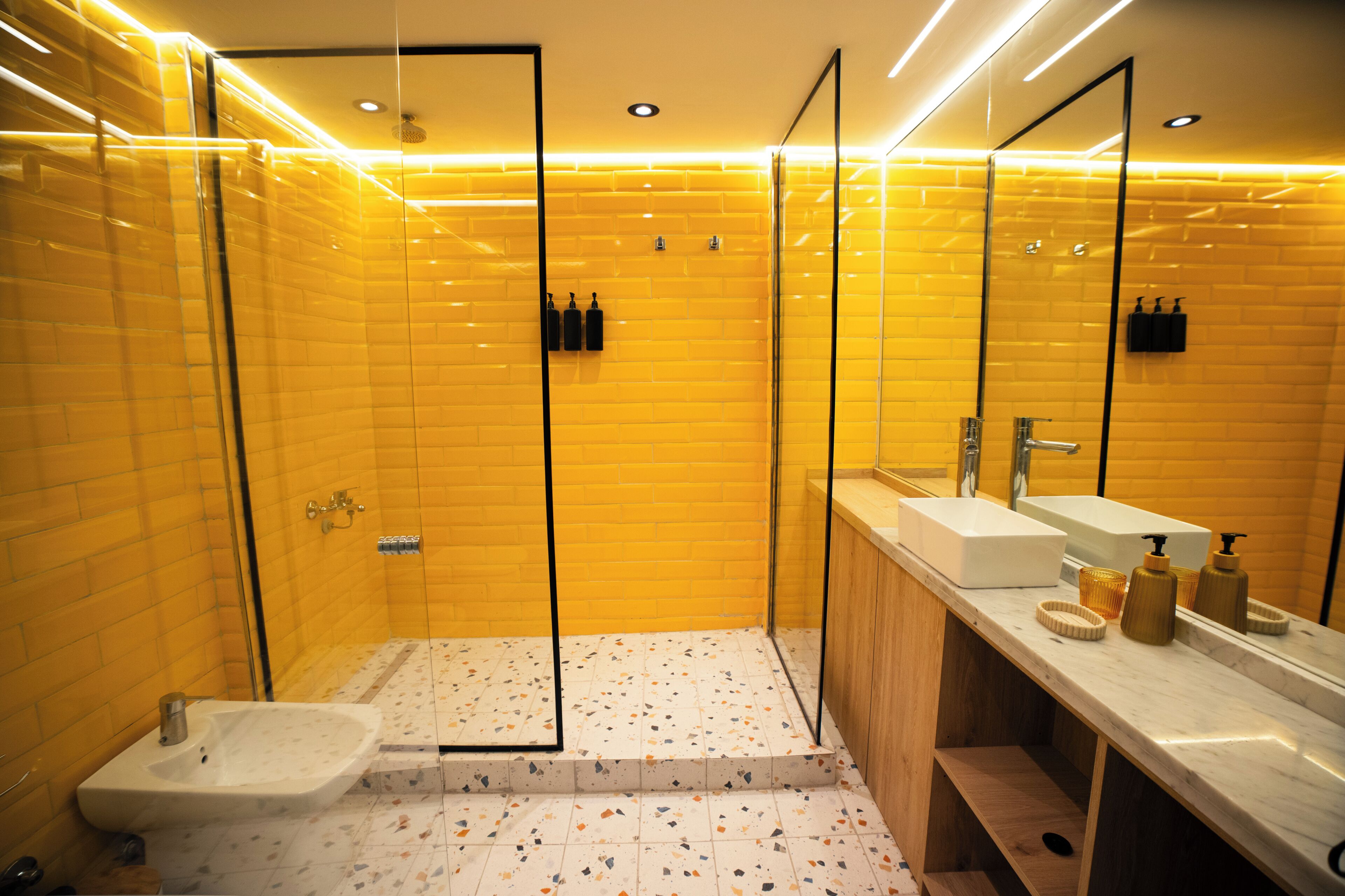 A modern bathroom with a glass shower enclosure, a white sink, and a vanity with a mirror.