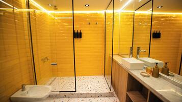 A modern bathroom with a glass shower enclosure, a white sink, and a vanity with a mirror.