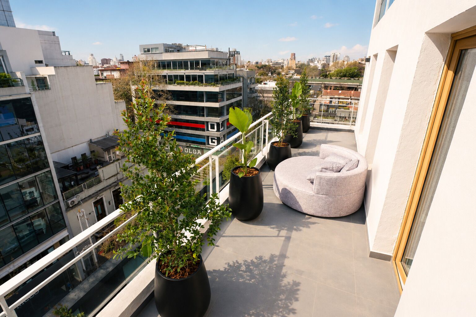 Un balcón con plantas en macetas, un espacio de estar circular y vistas a la ciudad.