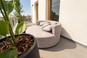 Un espacio al aire libre moderno con un banco redondo y acolchado, y una planta en maceta.