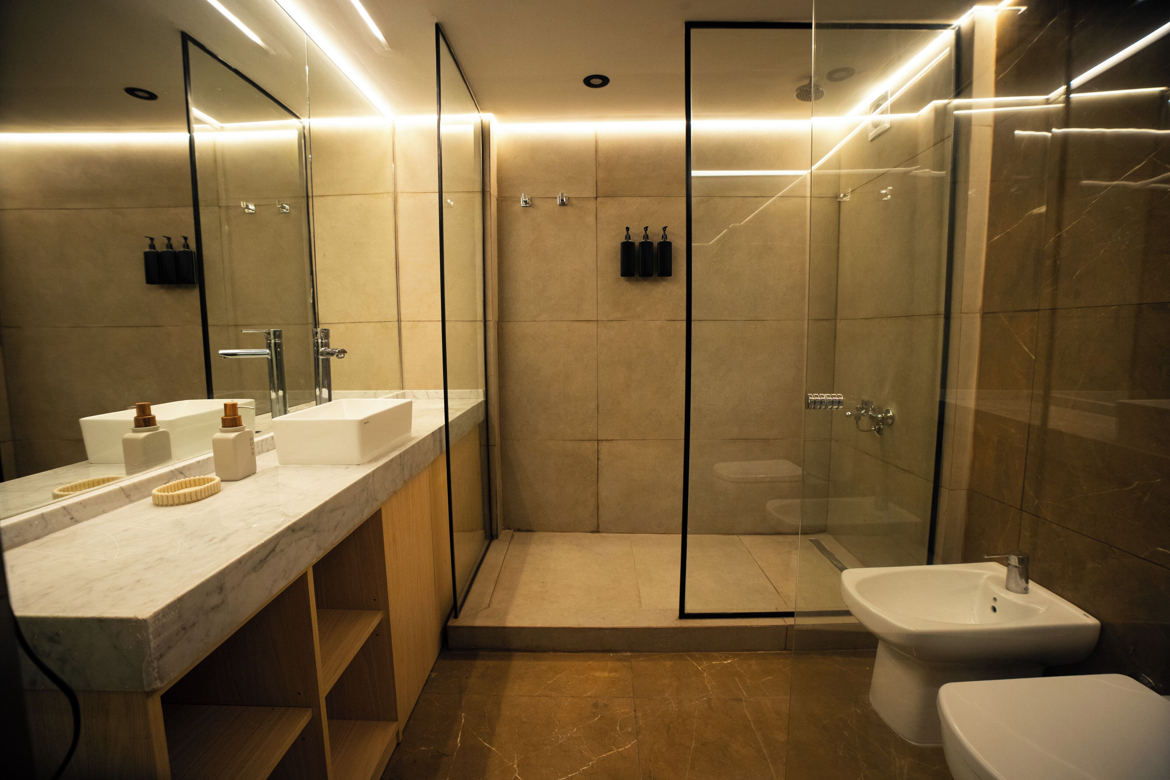 A modern bathroom with a glass-enclosed shower, a white sink, and a toilet.