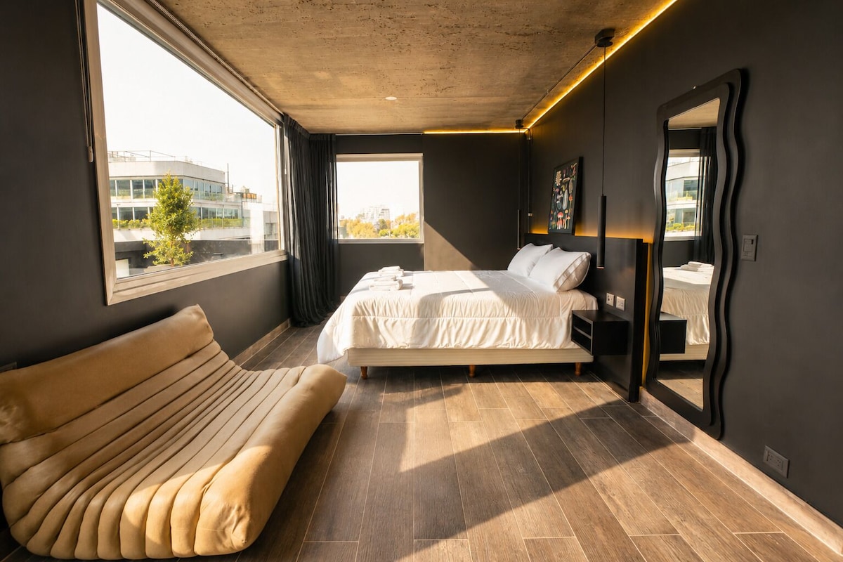 Un dormitorio moderno con una cama grande, un sofá y vistas a un edificio.
