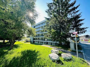 A modern building with a multi-story structure, a grassy area with rocks, and a clear sky. - Nr.06 Haus Sursilvana Appartement/Fewo,   Nr.06 Haus Sursilvana by Interhome (Lenzerheide)