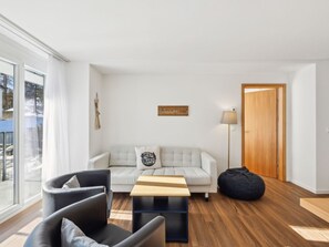 A modern living room with a sofa, chairs, a coffee table, and a wooden door. - Nr.06 Haus Sursilvana Appartement/Fewo,   Nr.06 Haus Sursilvana by Interhome (Lenzerheide)