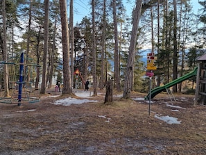 Ein Spielplatz mit einer Kletterkonstruktion, einer Rutsche und einem Wegweiser mit Richtungshinweisen.