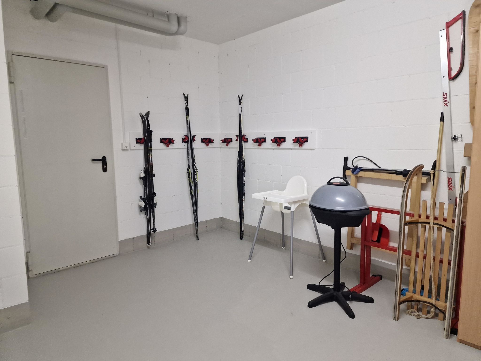 A room with white walls, a door, and skis mounted on the wall.