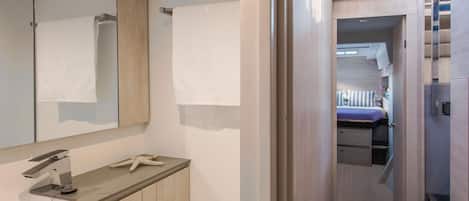 A modern bathroom with a large mirror, a towel rack, a sink, and a starfish decoration.