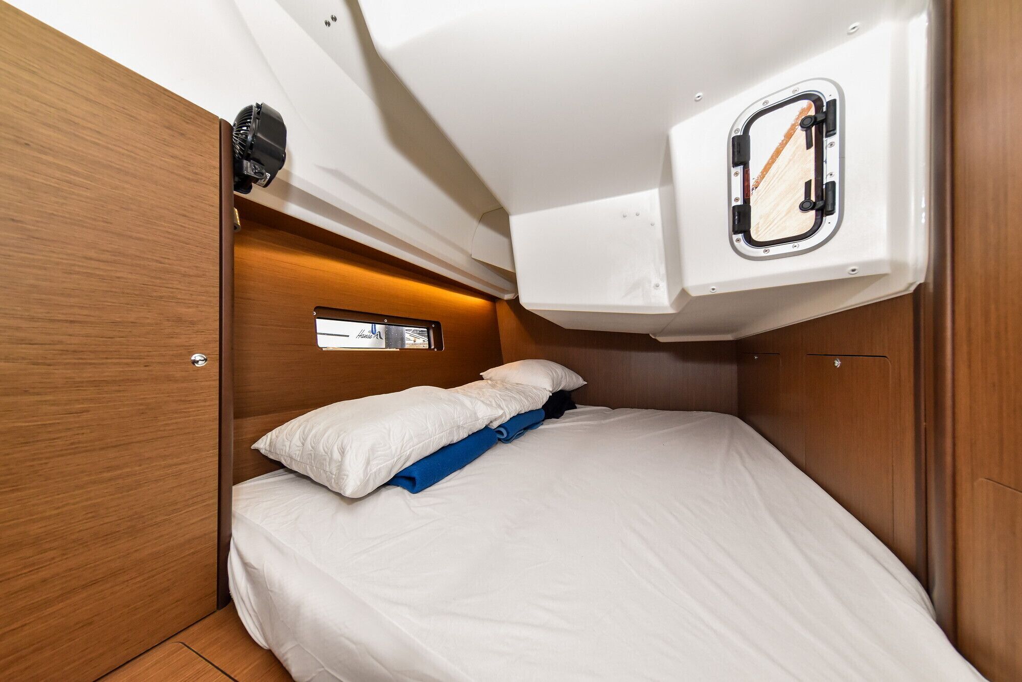 Une cabine compacte comprenant un lit simple, une petite fenêtre et un panneau de commande situé au-dessus du lit.