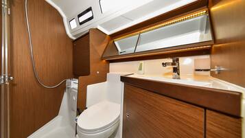 A compact bathroom with a toilet, shower, and sink.