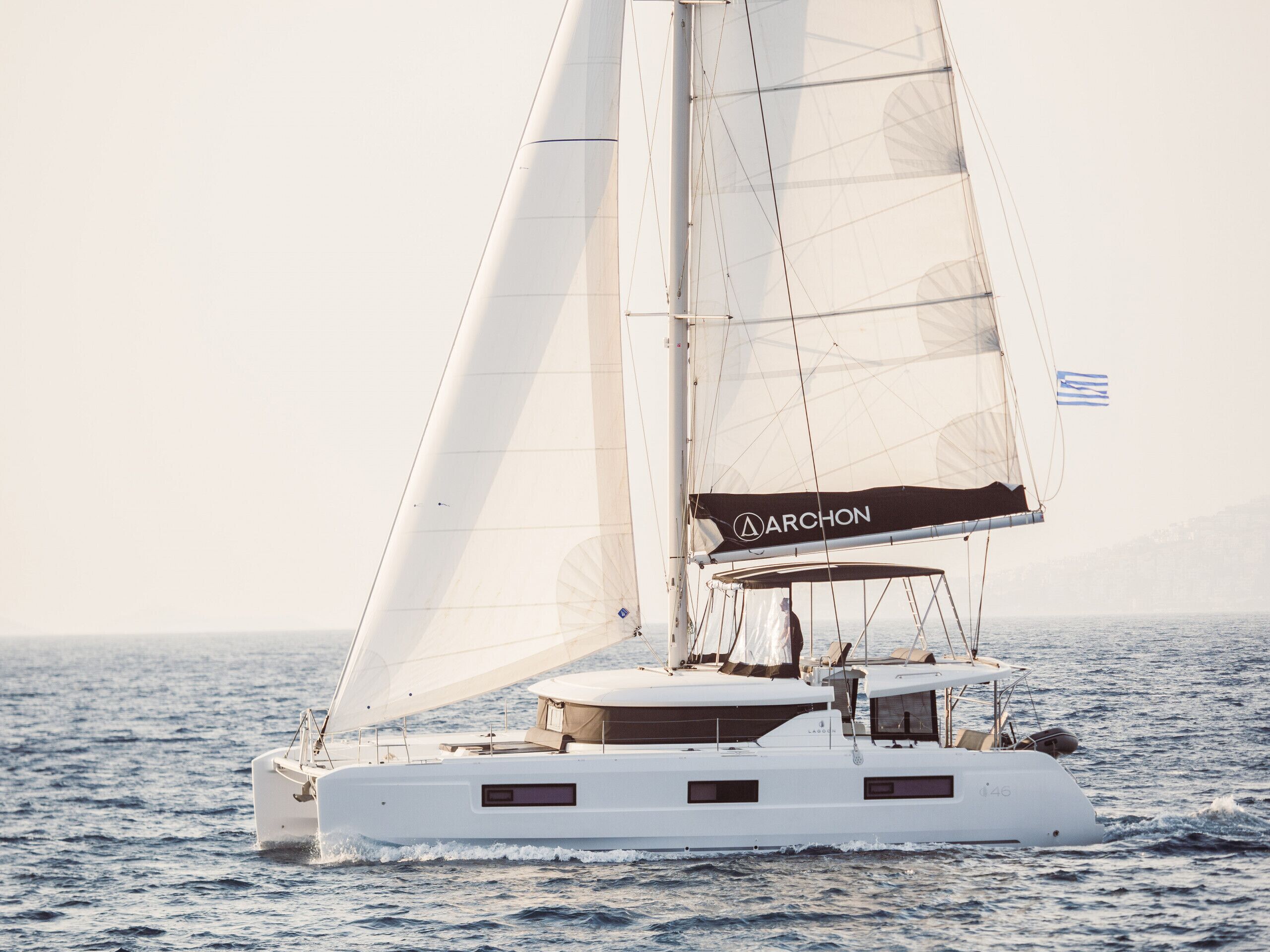 Eine Segelyacht mit Kabine und Flagge auf dem Wasser unterwegs.