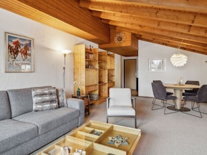 Ein stilvolles Wohnzimmer mit einer Couch, einem Couchtisch, einem Bücherregal und einem Essbereich mit Stühlen.