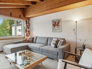 A cozy living room with a grey sofa, a glass coffee table, and a framed poster on the wall. - A301 Appartement/Fewo,   Ferienwohnung A301 by Interhome (Lenzerheide)