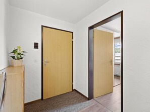 A hallway with a wooden door, a small potted plant, and a radiator. - A301 Appartement/Fewo,   Ferienwohnung A301 by Interhome (Lenzerheide)