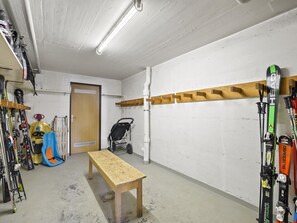 Ein Skiabstellraum mit einer Holzbank, Skiern und einem Kinderwagen.