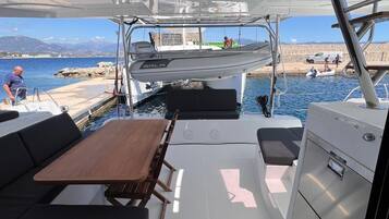 A boat's interior with a table, seating, and a control panel.