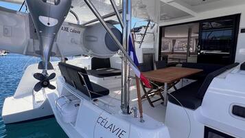A yacht with a cabin area featuring a table and chairs, a steering wheel, and a winch labeled '15'.