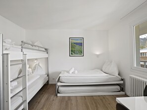 A compact room with bunk beds, a single bed, a framed landscape painting, a window with a view, and a radiator. - Nr.78 Haus Ladina Appartement/Fewo,   Nr.78 Haus Ladina by Interhome (Lenzerheide)