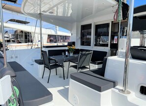 A boat deck with a table and chairs, a potted plant, and a view of the sea. - Sun-Kissed Sailing Adventure in Split, Croatia (Split)