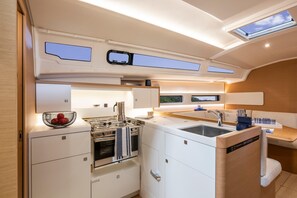 A compact galley kitchen with a stove, oven, sink, and a small window.