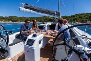 A sailboat with a wooden deck, a steering wheel, and a control panel.