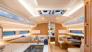 A yacht interior with a central dining area, a kitchen with a sink, and a seating area with a control panel. - Sun-Kissed Sailing Adventure in Northern Croatia (Opatija)
