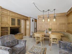 Un salon spacieux comprenant un coin repas, des meubles de rangement en bois et un téléviseur.