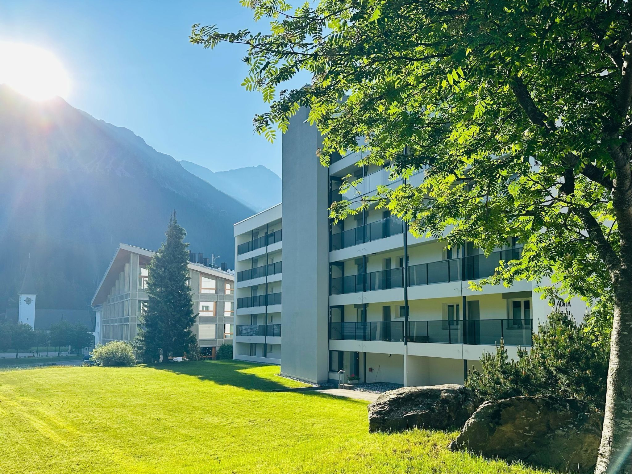 A modern building with multiple floors, surrounded by a well-maintained lawn and trees.