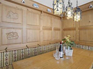 Ein Zimmer mit Holzvertäfelung, ausgestattet mit einem Esstisch, der für eine Mahlzeit gedeckt ist, inklusive einer Weinflasche und Gläsern.