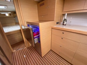 A compact kitchen with wooden cabinets, a built-in refrigerator, and a small countertop. - Sun-Kissed Sailing Adventure in Sibenik, Croatia (Primošten)