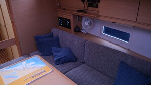Ein gemütlicher Wohnbereich mit einer Couch, Kissen, einem Tisch mit einer Karte und einem Bedienfeld mit Ventilator und Gerät.