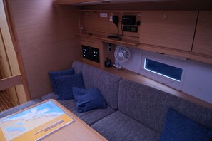 A compact living space with a sofa, pillows, a table with a map, and a control panel with a fan and a device. - Sun-Kissed Sailing Adventure in Sibenik, Croatia (Primošten)