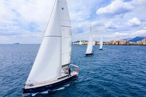 A sailboat on a calm sea with rocky coastline in the background. - Sun-Kissed Sailing Adventure in Sibenik, Croatia (Primošten)