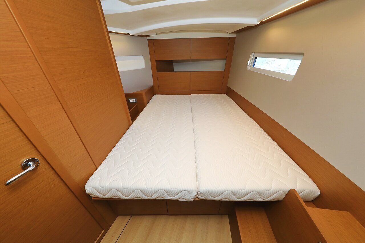 A compact, well-lit interior with a single bed, wooden paneling, and a small window.
