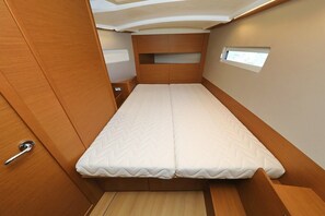 Un intérieur compact et bien éclairé, avec un lit simple, un lambris en bois et une petite fenêtre.