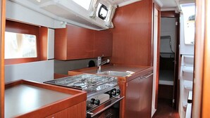 Een kleine keuken met een gasfornuis, spoelbak en houten keukenkastjes.