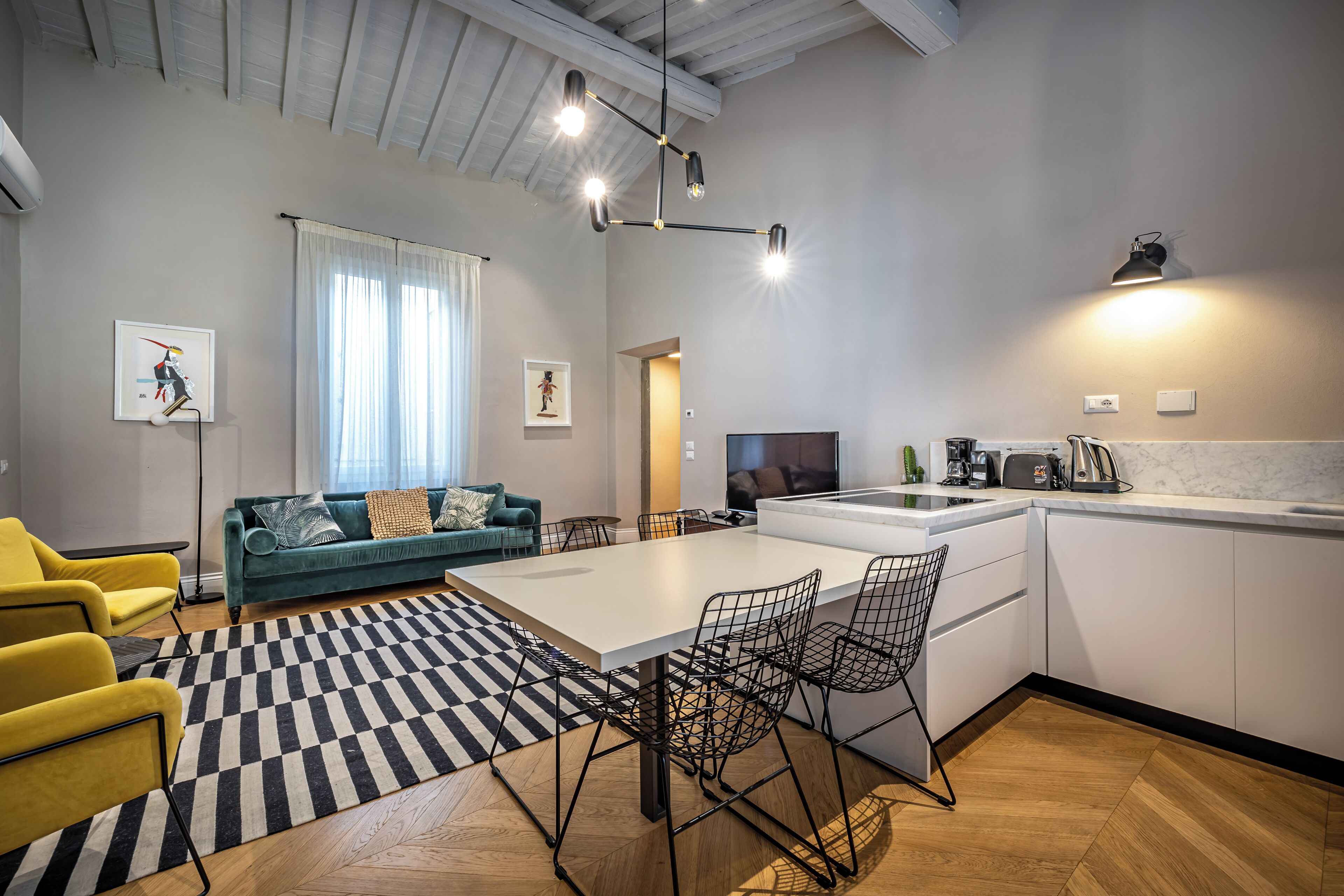 A modern kitchen with a dining area, a sofa, and a TV.