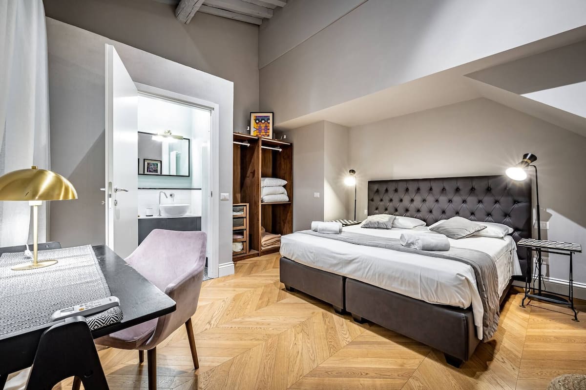 Ein modernes Schlafzimmer mit einem großen Bett, Nachttischen, einem Schreibtisch und einem Kleiderschrank.
