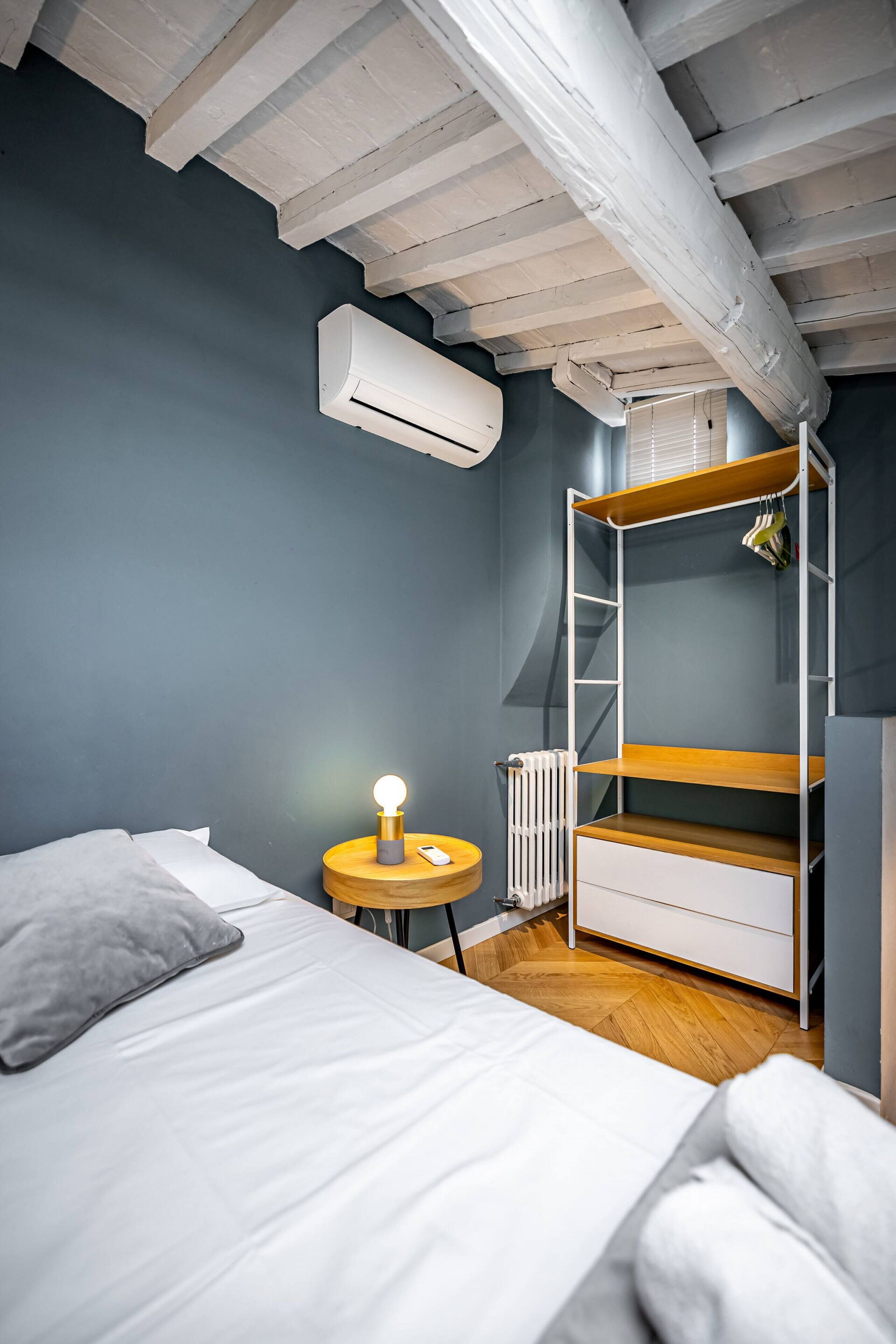 A bedroom with a bunk bed, a bedside table with a lamp, and an air conditioning unit.