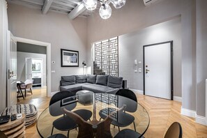Ein modernes Wohnzimmer mit einem Ecksofa, einem Glastisch und einem Essbereich mit Stühlen.