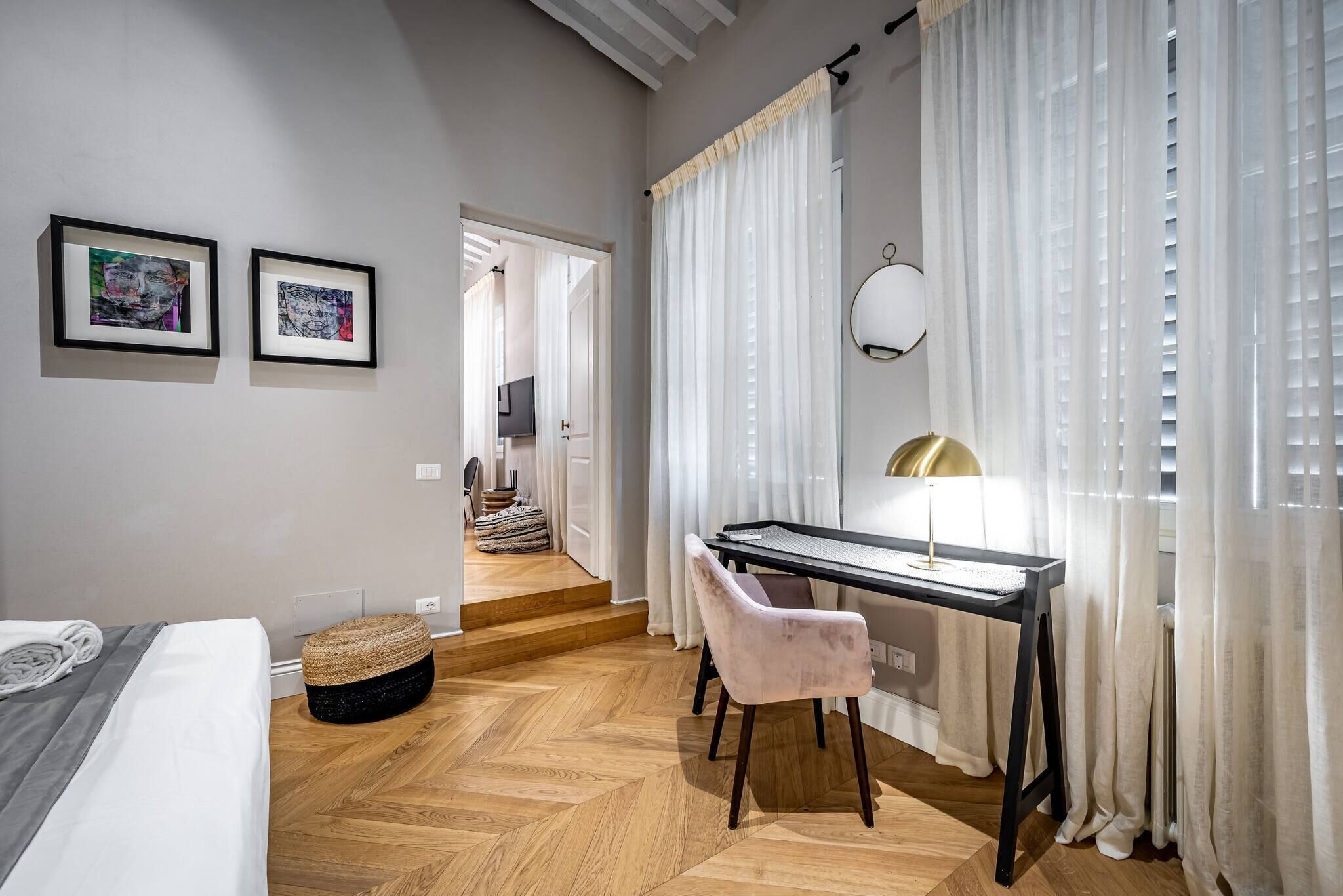 A modern bedroom with a bed, a desk, and a chair. There are two framed artworks on the wall.